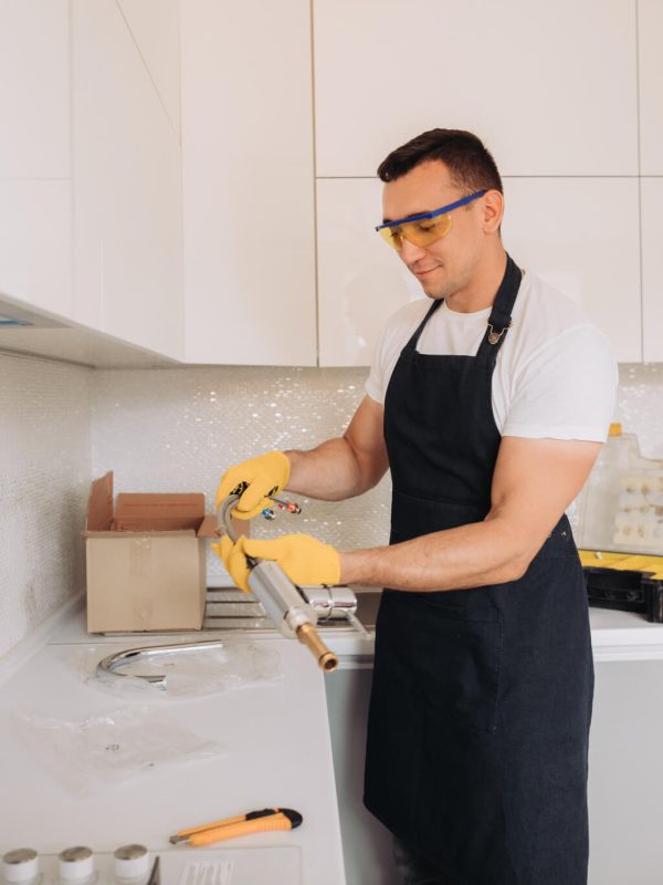 Plumber installing plumbing equipment in the kitchen