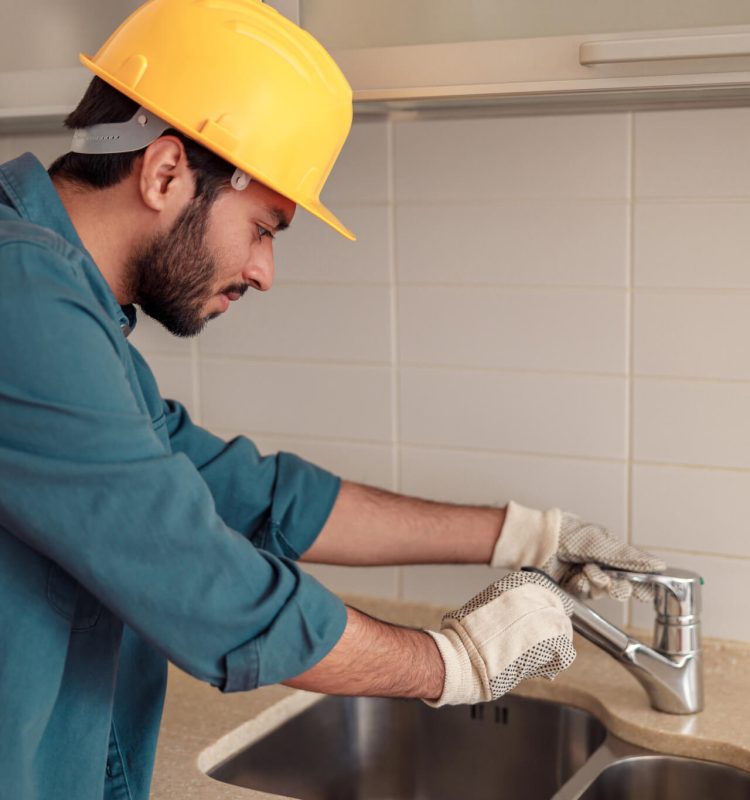 plumber repairing sink faucet at customer kitchen